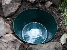 a green bowl sitting on top of some rocks