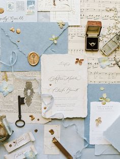 an assortment of wedding stationery items on top of blue paper with gold and white accents