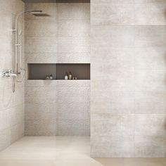 a walk in shower sitting next to a white tiled wall with shelves on each side