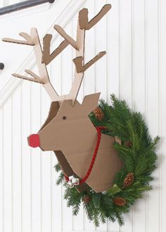 a cardboard reindeer head hanging from the side of a wall next to a christmas wreath