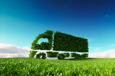 a truck made out of green leaves on top of a lush green field with blue sky in the background