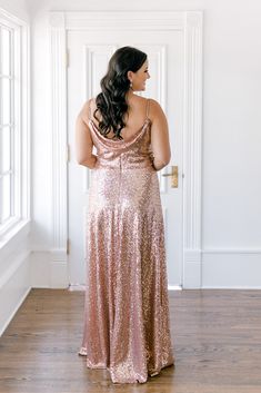 a woman in a pink sequin dress looking off into the distance with her back to the camera