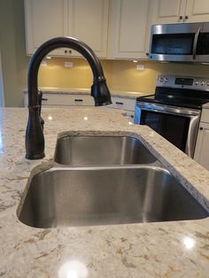 a kitchen with an island sink and stainless steel appliances