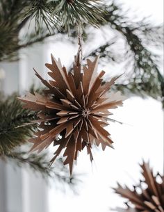 an ornament hanging from a christmas tree with brown paper stars on the top