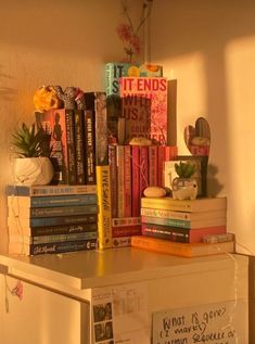 there is a refrigerator with many books on the top and bottom shelf next to it