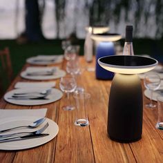 a wooden table topped with white plates and silverware