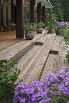 a wooden deck with potted plants and purple flowers