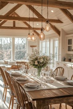 a dining room table is set with place settings and flowers in vases on the table