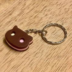 a wooden keychain with a brown and pink cat on it's side