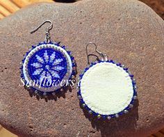 two blue and white beaded earrings sitting on top of a piece of stone next to each other