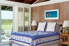 a bedroom with wood paneling and blue bedding in front of sliding glass doors