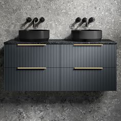 two black sinks sitting next to each other on top of a counter in front of a gray wall