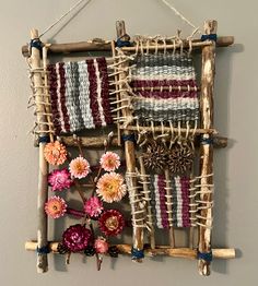 a wall hanging made out of sticks and yarn with flowers in the middle on it