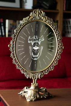 a clock with a face on it sitting on a table in front of a red couch