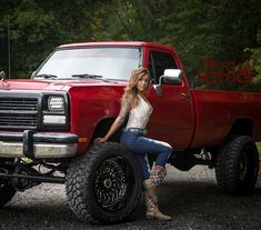 a woman sitting on the tire of a red truck