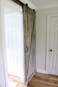 an open wooden door in a white room with hardwood floors and hard wood flooring