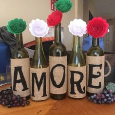 four wine bottles with flowers in them sitting on a table