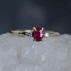 a close up view of a ring with a pink stone and three white diamonds on top