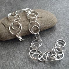 This unusual bracelet features smooth round links of sterling silver wire in two different shapes. There are small round plain links, and larger links with small ones looped inside them alternating along the length of the bracelet and ending with a sturdy lobster claw catch. A pleasing design, with the looped links adding that bit of extra detail to make this bracelet really special. Each and every link has been soldered closed, meaning your bracelet is secure and safely on your wrist!  This pre Minimalist Sterling Silver Bracelet With Oval Link Box Chain, Silver Chain Bracelet With Solid Links, Adjustable Oval Link Silver Chain Bracelet, Nickel-free Sterling Silver Oval Link Bracelets, Nickel-free Adjustable Sterling Silver Oval Link Bracelet, Silver Chain Bracelet, Silver Wire, Chain Link Bracelet, Link Bracelets