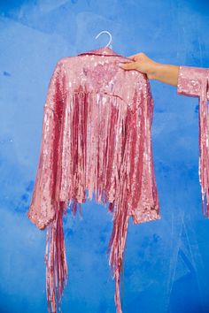 This MINI KIDS PINK SEQUIN FRINGE JACKET is a fun and fashionable gameday look. Featuring an all-over pink sequin design with edgy fringe detail, this jacket helps your little one stand out from the stands and show their team spirit. All orders are currently shipping within 14 business days. To receive item quicker, expedited shipping is available at checkout. Pink Sequined Outerwear For Spring, Pink Long Sleeve Outerwear For Party Season, Party Outerwear With Tassels, Long Sleeve Party Outerwear With Tassels, Spring Party Outerwear With Rhinestone Fringe, Fall Party Outerwear With Rhinestone Fringe, Pink Sequined Outerwear For Winter, Sparkly Fringe Jacket, Tinsel Fringe Jacket