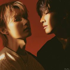 two young men standing next to each other in front of a red background with the sun shining on them