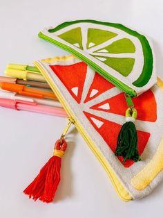 a lemon slice on top of a zippered pouch next to markers and pencils