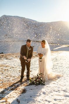 a bride and groom standing in the snow