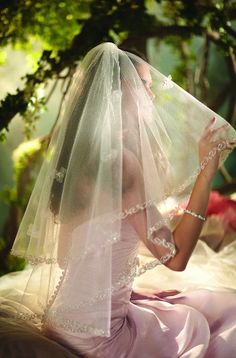 a woman wearing a wedding veil sitting on a bed