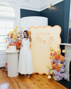 a woman standing next to a sign with flowers on it