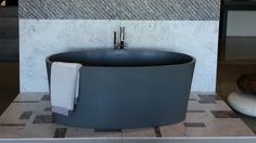 a bath tub sitting on top of a tiled floor next to a wall mounted faucet