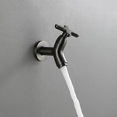 the faucet is attached to the wall with water running from it's spout