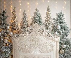 an ornate white bed surrounded by christmas trees and garlands with lights on the wall