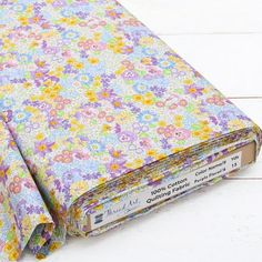 an old book covered in colorful flowers on a white wooden surface with the cover folded down