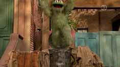 a large green monster standing on top of a trash can