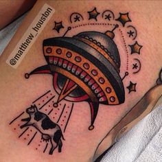 a tattoo on the leg of a woman with an alien ship flying over her head