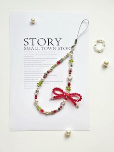 a necklace with a red bow on it and pearls hanging from the end of it