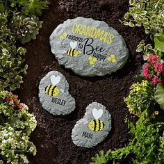 three bee stepping stones in the dirt surrounded by flowers and plants with words on them