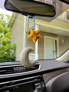 a car dashboard with a stuffed animal hanging from it's dash board in front of a house