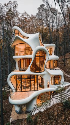 an unusual house in the woods with stairs leading up to it and lots of windows