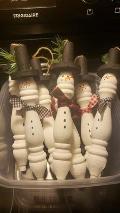 snowmen in hats and bow ties are sitting in a plastic container on the stove