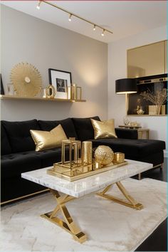 a living room with black couches and gold accents on the tables in front of it