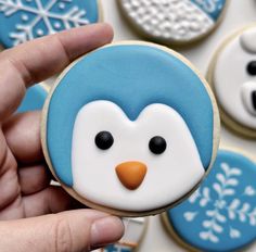 a hand holding a cookie decorated like a penguin