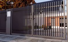 a large metal gate is open on the side of a building in front of a tree