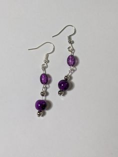 Elevate your jewelry collection with these lovely purple beaded dangling earrings. The round shape and silver tone metal create a chic and sophisticated look, while the hook closure ensures comfortable wear.  Only the best materials are used to create each piece of jewelry  - Glass beads  - Acrylic beads  - Silver tone components Purple Metal Drop Earrings, Purple Metal Dangle Earrings, Purple Dangle Metal Earrings, Purple Metal Earrings With Dangling Beads, Purple Beaded Dangle Earrings, Purple Drop Earrings With Dangling Beads, Purple Round Metal Earrings, Purple Dangling Beads Chandelier Earrings, Purple Dangle Beaded Earrings