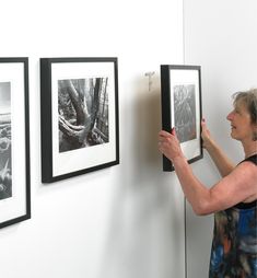 a woman is looking at pictures on the wall and holding them in front of her