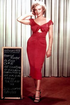 a woman in a red dress standing next to a chalkboard