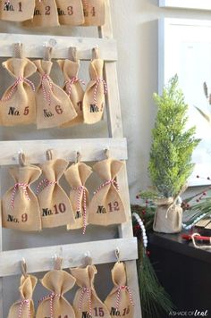 burlap bags are hung on a ladder with twine ribbons and numbered numbers