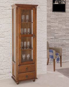 a tall wooden cabinet with wine glasses on the front and bottom shelves, against a white brick wall