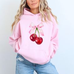 "Be on top of the trends with our \"Pink Bow Cherries\" Hoodie Sweatshirt - the sweetest addition to your wardrobe! Irresistibly Charming: Adorned with a delightful pair of red cherries and a cute pink bow, this cozy Gildan hoodie sweatshirt is a fashion statement that blends sweetness with style.  Perfect for wearing oversized with your favorite sweats or leggings for a day of shopping or with a pair of jeans for a night on the town.  Adorable for school with a pink hair bow too!  Make a statement with every wear! Choices That Pop: Available in 8 yummy colors and 7 sizes, you can now express your unique style effortlessly. It is sure to become your new favorite everyday sweatshirt!  Created with direct-to-garment printing to insure the most crisp, vibrant and long lasting image, our soft Casual Pink Winter Sweatshirt, Pink Winter Hoodie, Cute Spring Hooded Sweatshirt, Cute Hooded Sweatshirt For Spring, Pink Cotton Hoodie Sweatshirt, Pink Cotton Hoodie Top, Pink Long Sleeve Hoodie With Drawstring Hood, Pink Long Sleeve Hoodie With Drawstring, Pink Long Sleeve Sweatshirt With Drawstring Hood