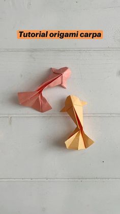 two origami birds sitting next to each other on top of a white wall